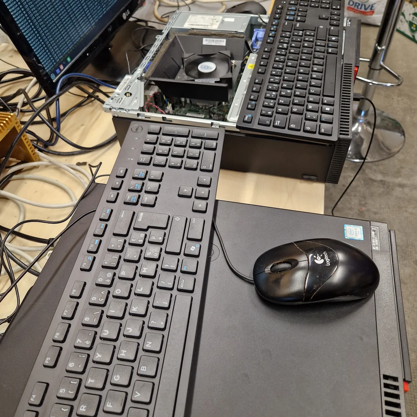 Établi de l'association RACK : unité centrale ouverte, claviers, souris et mini PC en cours de démontage