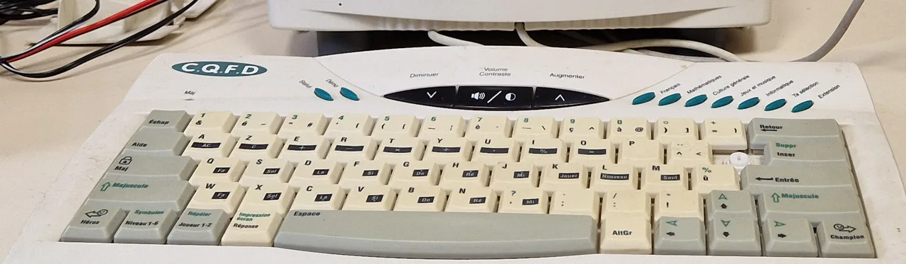 Clavier AZERTY de la Station PC : touches de calculatrice sous les lettres A à P, notes de musique sous les rangées inférieures, touches Niveau 1-6, Joueur 1-2, Héros et Champion, boutons de rubriques en haut à droite